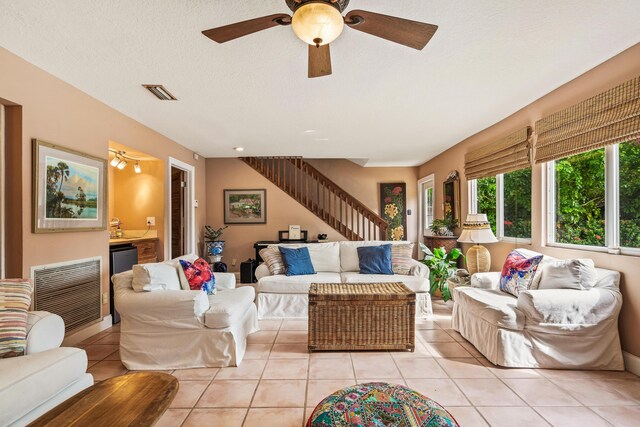 tiled living room with ceiling fan and a textured ceiling