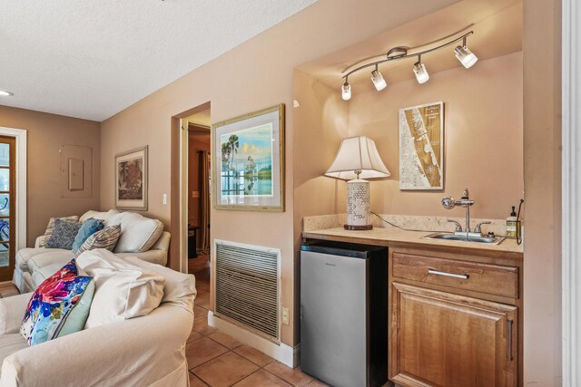 interior space featuring a textured ceiling, track lighting, tile patterned flooring, and vanity