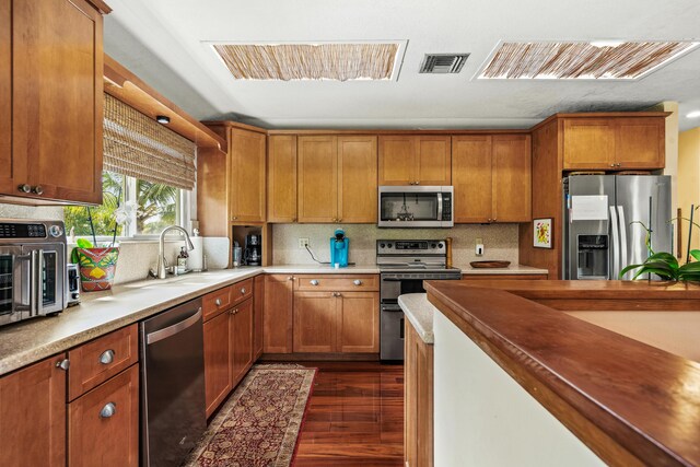 kitchen featuring appliances with stainless steel finishes, dark hardwood / wood-style flooring, sink, and backsplash