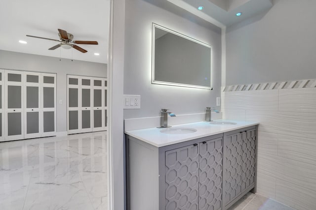 bathroom featuring ceiling fan, vanity, tile patterned floors, and tile walls