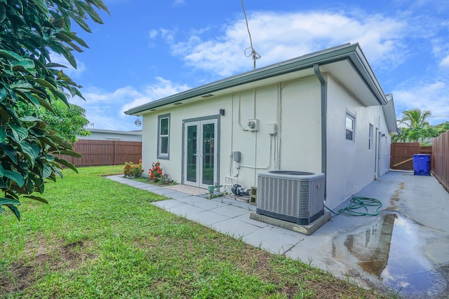 rear view of property with a lawn, a patio, french doors, and central AC