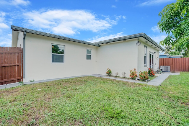 rear view of property with a lawn and central AC unit