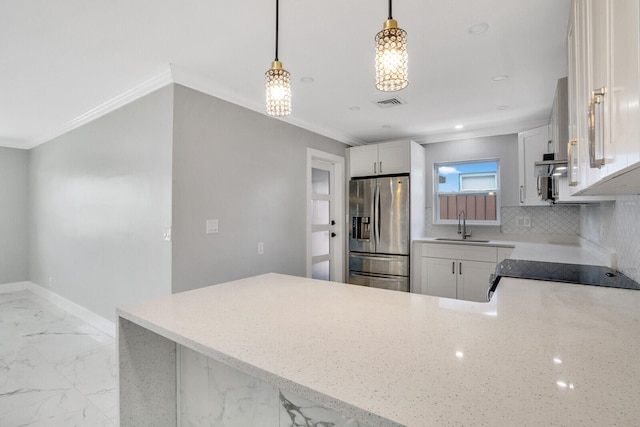 kitchen featuring white cabinetry, tasteful backsplash, sink, pendant lighting, and stainless steel fridge