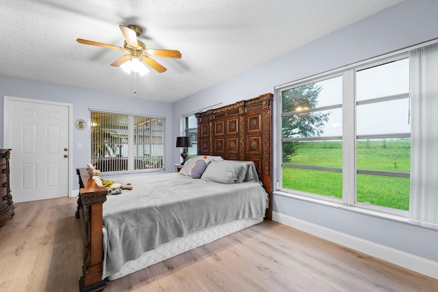 bedroom featuring multiple windows, a textured ceiling, ceiling fan, and light hardwood / wood-style flooring