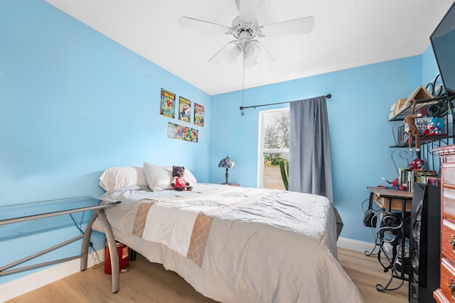 bedroom with light wood-type flooring, ceiling fan, and a textured ceiling