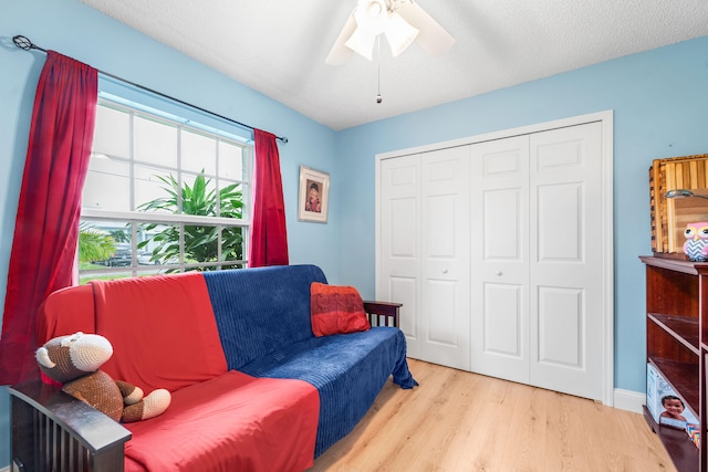 sitting room with ceiling fan, a textured ceiling, and light hardwood / wood-style floors