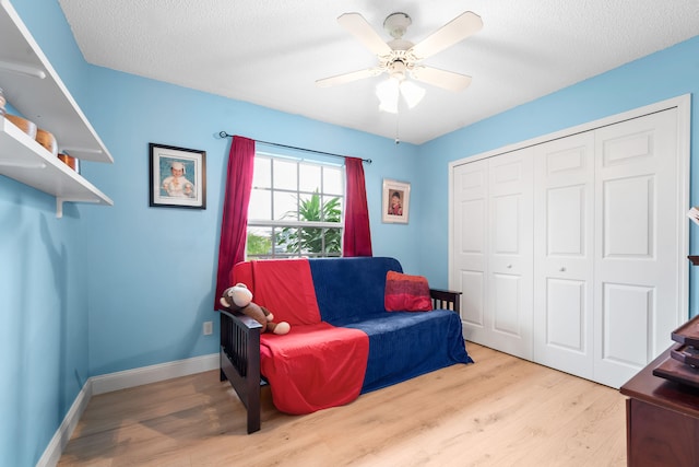 sitting room featuring light hardwood / wood-style floors, ceiling fan, and a textured ceiling