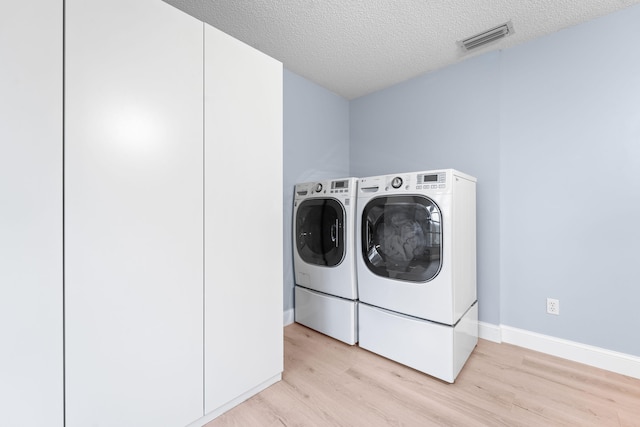 laundry area featuring a textured ceiling, light hardwood / wood-style floors, and independent washer and dryer