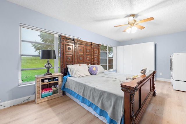 bedroom featuring washer / dryer, light hardwood / wood-style floors, ceiling fan, and a textured ceiling