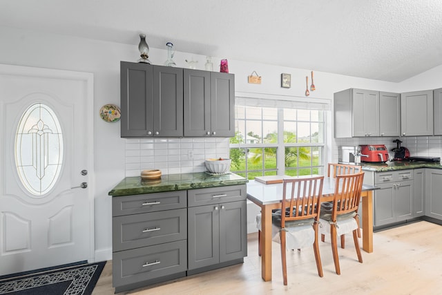 kitchen featuring gray cabinetry, light hardwood / wood-style flooring, and tasteful backsplash