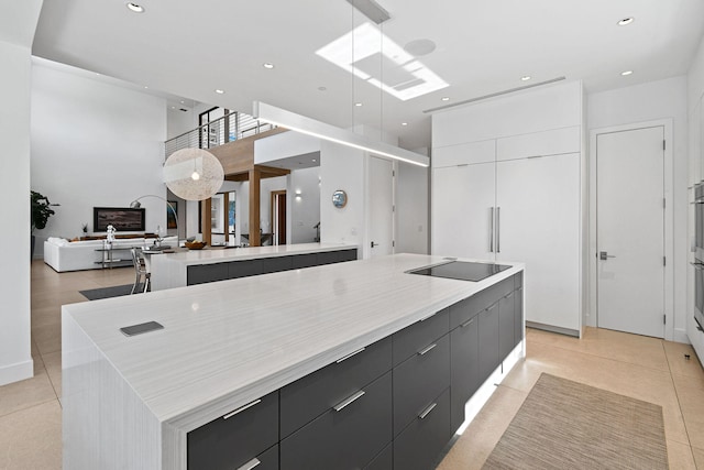 kitchen featuring a spacious island, pendant lighting, black electric cooktop, and white cabinets