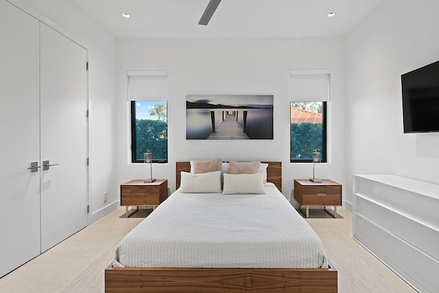 bedroom with multiple windows, ceiling fan, a closet, and light colored carpet