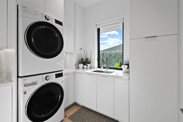 clothes washing area featuring cabinets, light tile patterned floors, sink, and stacked washer and dryer