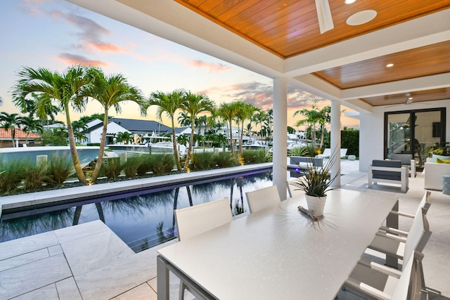 pool at dusk featuring an outdoor living space, a patio area, and ceiling fan