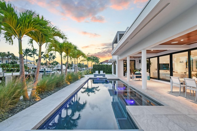 pool at dusk featuring a patio