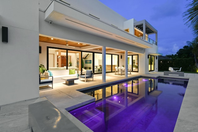 pool at dusk with an outdoor hangout area, ceiling fan, and a patio area