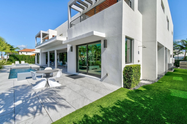 back of house featuring a patio, a balcony, and a lawn