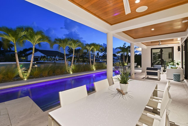 pool at dusk with an outdoor living space, ceiling fan, and a patio