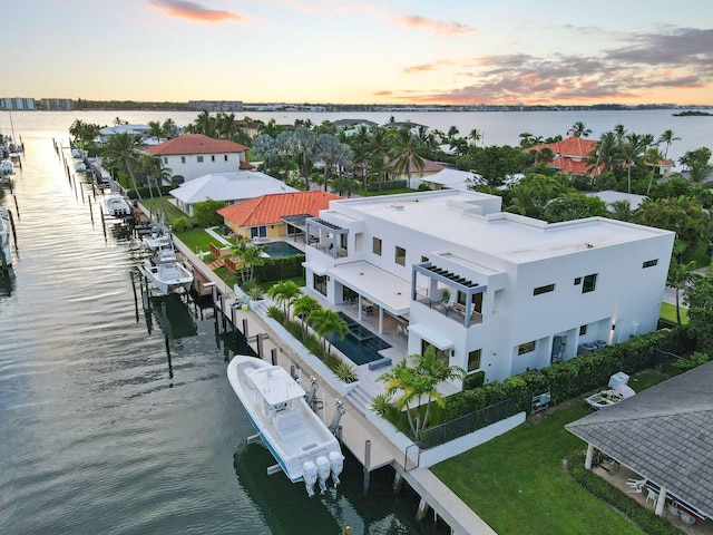 aerial view at dusk featuring a water view