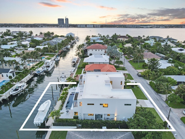 aerial view at dusk featuring a water view