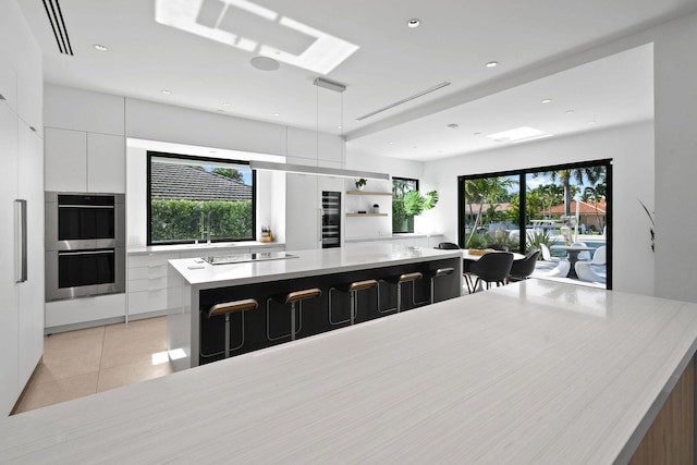 kitchen featuring plenty of natural light, a breakfast bar area, a spacious island, and white cabinetry