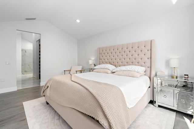 bedroom featuring vaulted ceiling, connected bathroom, and wood-type flooring