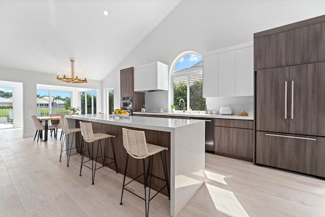 kitchen with light hardwood / wood-style flooring, decorative light fixtures, white cabinets, a kitchen breakfast bar, and a center island