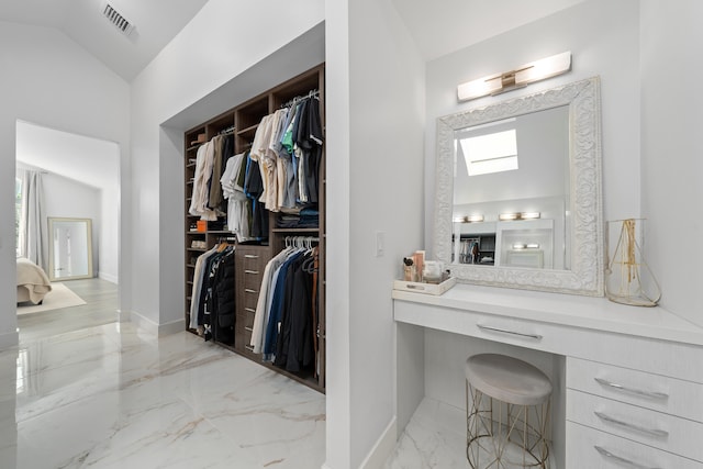 spacious closet with light tile patterned flooring and vaulted ceiling with skylight