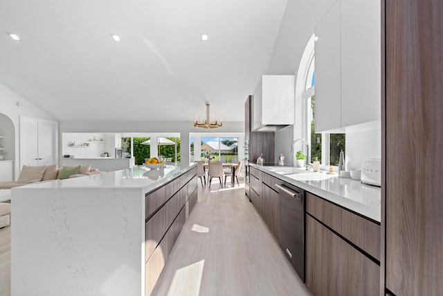 kitchen featuring white cabinetry, stainless steel dishwasher, sink, and light hardwood / wood-style flooring