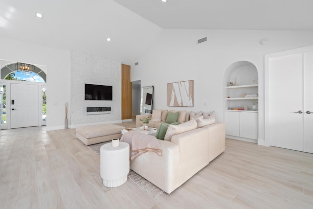 living room with light hardwood / wood-style flooring, vaulted ceiling, and built in shelves