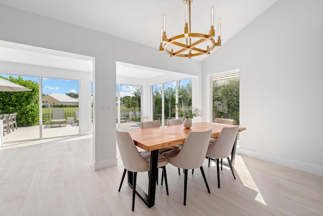 dining area featuring high vaulted ceiling, a chandelier, and light wood-type flooring