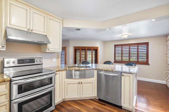 kitchen featuring a healthy amount of sunlight, under cabinet range hood, appliances with stainless steel finishes, and cream cabinetry