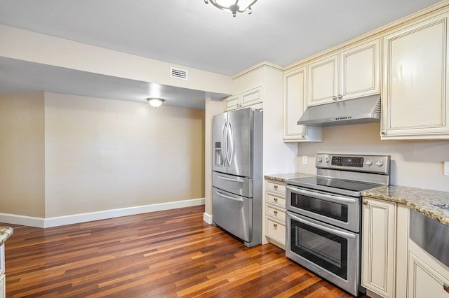 kitchen featuring dark wood-style floors, cream cabinetry, stainless steel appliances, visible vents, and under cabinet range hood