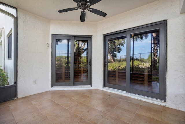 property entrance with a ceiling fan and stucco siding