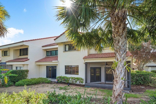 view of front of property with ceiling fan, a tiled roof, a sunroom, and stucco siding