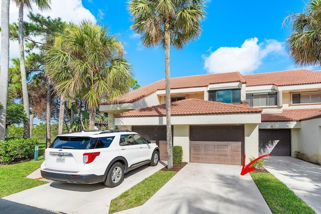 townhome / multi-family property with driveway, an attached garage, a tile roof, and stucco siding