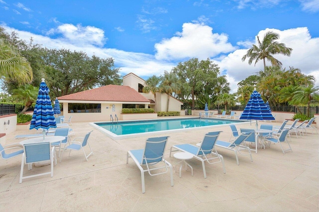 community pool with a patio area and fence