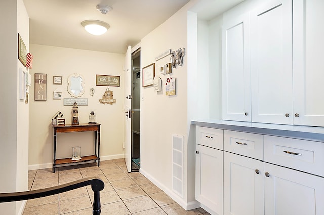 hall with light tile patterned flooring and baseboards