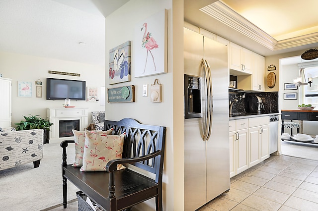 kitchen with light colored carpet, a tray ceiling, white cabinetry, sink, and stainless steel appliances