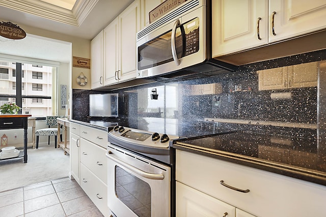 kitchen featuring light tile patterned floors, stainless steel appliances, ornamental molding, backsplash, and dark countertops