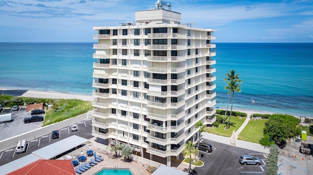 exterior space with a water view, a beach view, and a community pool