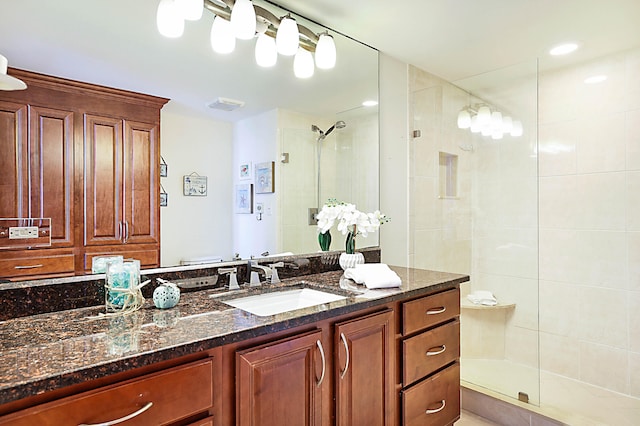 bathroom featuring a shower with shower door and vanity