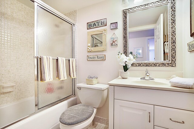 full bathroom with toilet, bath / shower combo with glass door, and vanity