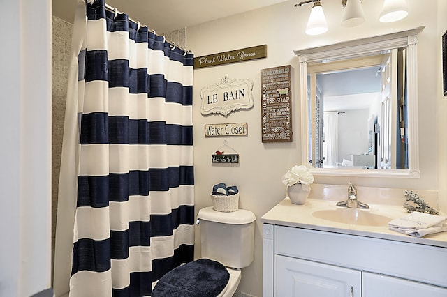 bathroom featuring toilet, vanity, and curtained shower