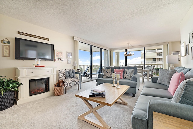 living area with a chandelier, a textured ceiling, light carpet, expansive windows, and a glass covered fireplace