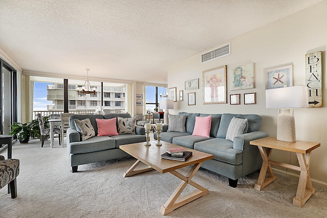 living room featuring light carpet, a textured ceiling, a chandelier, and visible vents