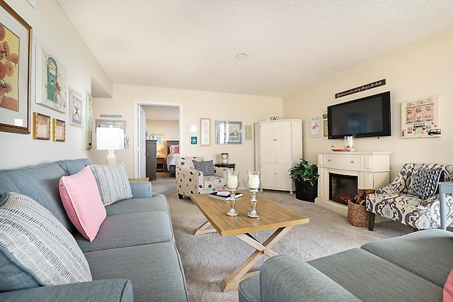 living area featuring light carpet, a textured ceiling, and a glass covered fireplace