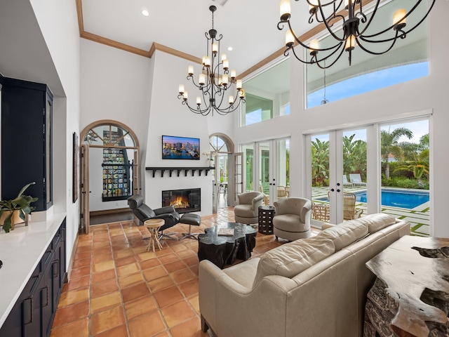 living room featuring light tile patterned flooring, a high ceiling, ornamental molding, an inviting chandelier, and french doors