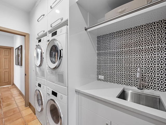 washroom with sink, light tile patterned floors, cabinets, and stacked washer / dryer