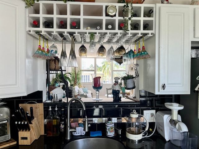 bar with sink, decorative backsplash, and white cabinets